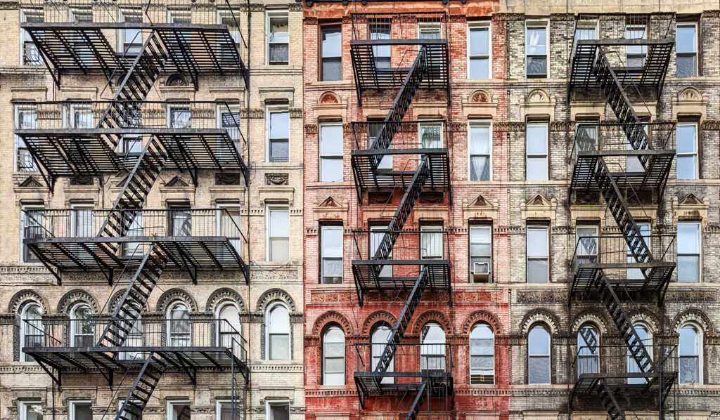 Exterior view of old New York City style architecture apartment building with windows and fire escapes.

Credit: iStock.com/deberarr